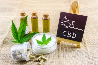 Vollspektrum CBD und THC Cannabisöle, Pillen und Cbd-Lotion auf Hanftuch mit chemischer Struktur auf Tafel