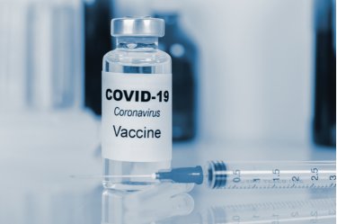 Covid-19 Impfstoff in einem Glas mit beiliegender Spritze